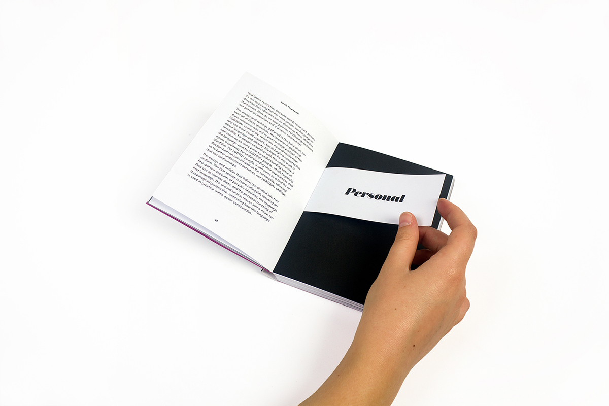 The book open to a spread in the middle. The left page has body text in a sans serif font. The right page is solid black, and there is a bind-in which reads "Personal" in the title font. A hand reaches in from the bottom edge of the image to partially lift the bind-in.